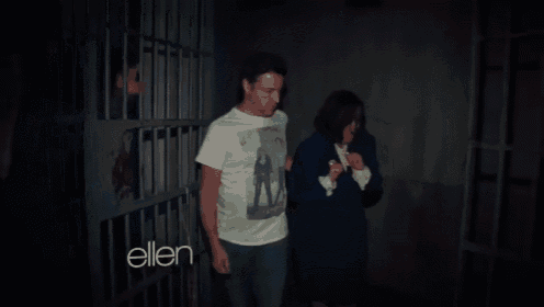a man and a woman are standing in a dark room with the words ellen on the bottom