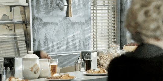 a woman sits at a table with plates of food and drinks