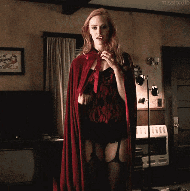 a woman in lingerie and a red cape is standing in a room with the hashtag missfordtb
