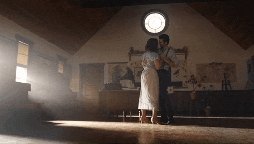a man and a woman are dancing in a room with a gramophone in the background