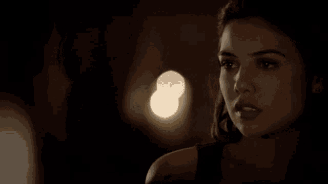 a close up of a woman 's face in the dark with a blurry background .