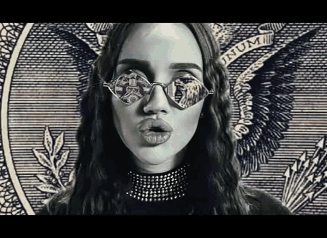 a woman wearing sunglasses is standing in front of a dollar bill