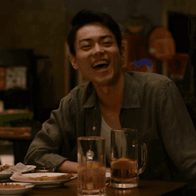 a man sitting at a table with a mug of beer