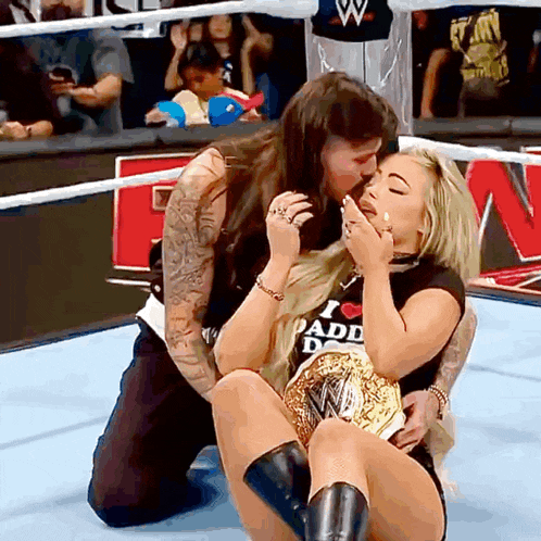 a woman kissing another woman who is wearing a shirt that says " i love dad "