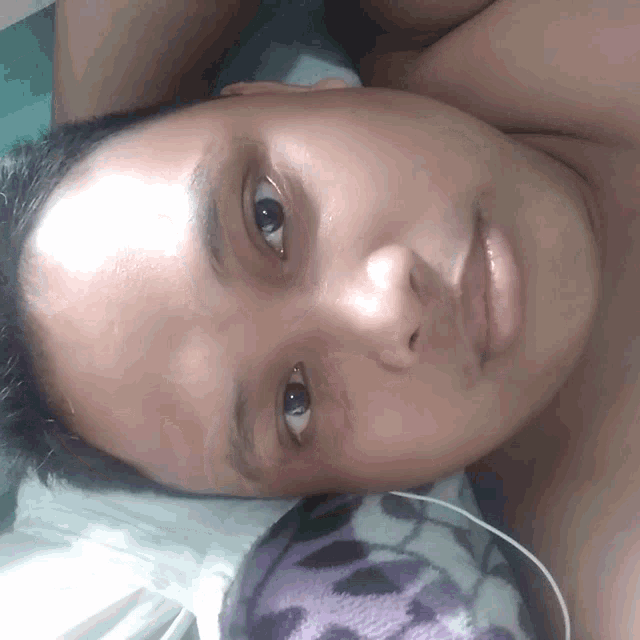 a close up of a man 's face with a purple blanket in the background