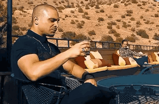 a man in a black shirt is sitting in a chair holding a glass of wine