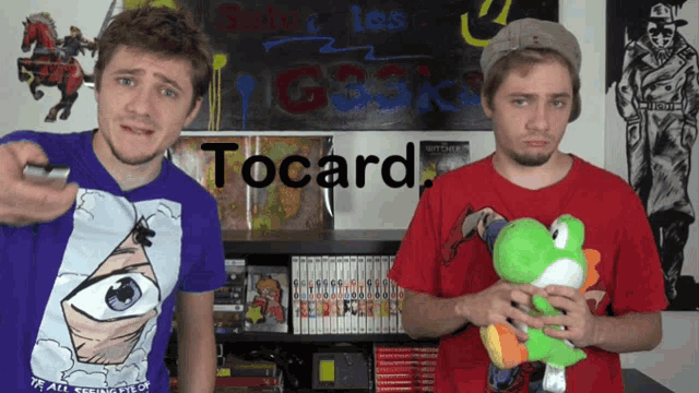 two men are standing next to each other with the word tocard written on the wall behind them