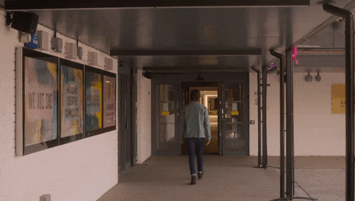 a man walks through a hallway with a sign that says we are one