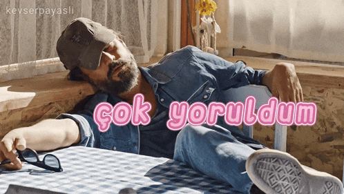 a man with a beard is laying on a table with the words " çok yoruldum " written above him