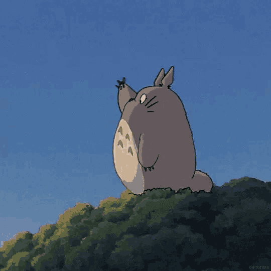 a cartoon totoro is standing on top of a tree .