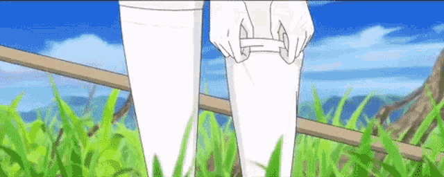 a person is standing in the grass tying their socks .