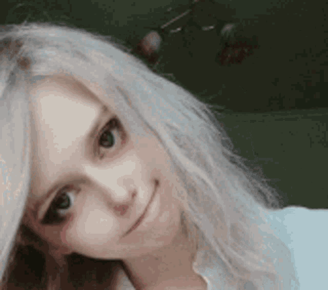 a close up of a woman 's face with white hair and green eyes .
