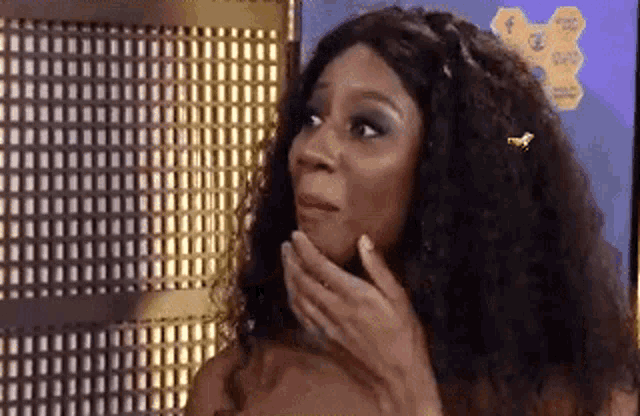 a woman with a bee in her hair is covering her mouth with her hand .