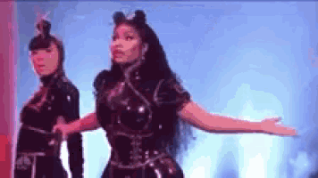 two women are dancing on a stage with their arms outstretched in front of a blue background .