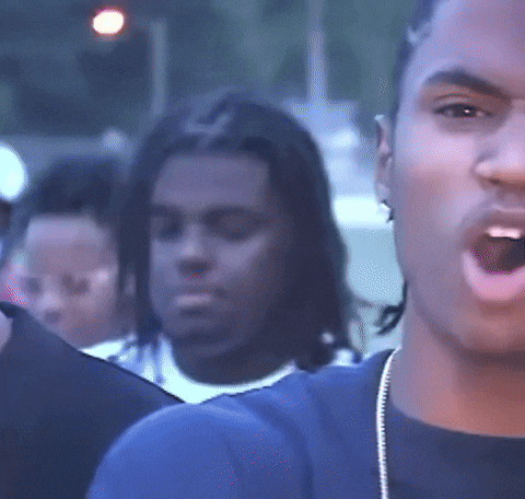 a man with dreadlocks is standing in a crowd of people with his mouth open .