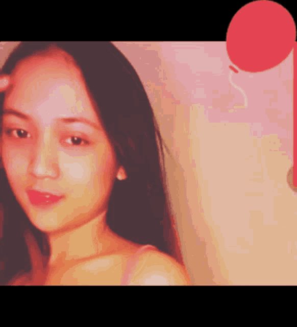 a woman is standing in front of a pink wall with a balloon in the background
