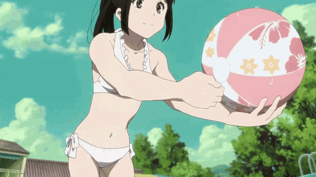 a girl in a bikini is holding a beach ball with flowers on it