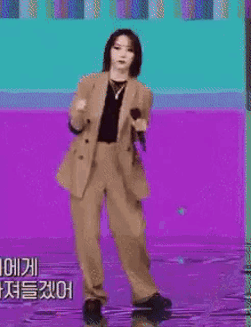 a woman in a suit is holding a microphone and dancing on a stage