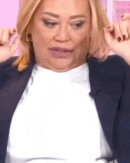 a close up of a woman wearing a white shirt and a blue jacket making a funny face .