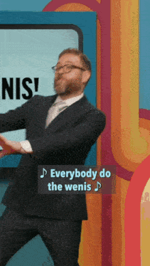 a man in a suit and tie is dancing in front of a screen that says everybody do the wenis