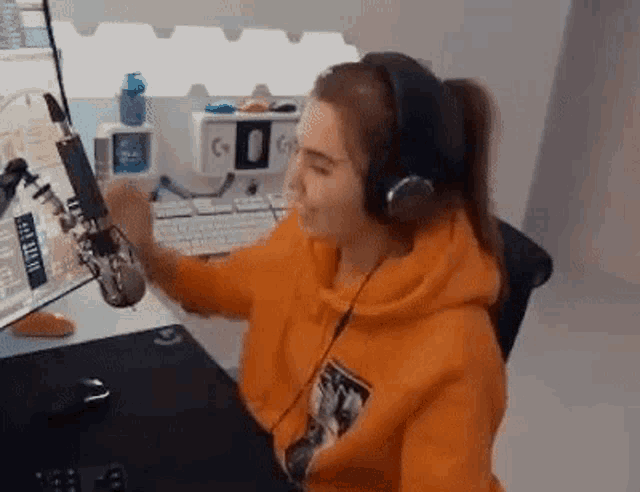 a woman wearing headphones is sitting at a desk in front of a computer and microphone .