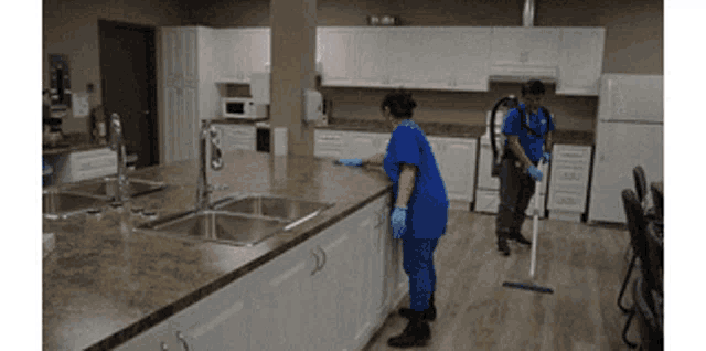 a woman in a blue shirt is cleaning a counter in a kitchen