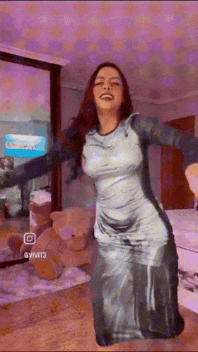 a woman in a long dress is dancing in a room with teddy bears and a mirror .