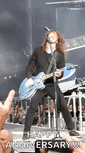a man is singing into a microphone while playing a guitar on a stage .