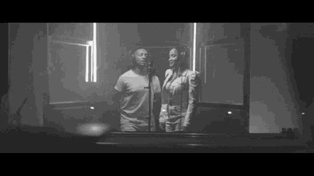 a man and a woman are singing into microphones in a studio .