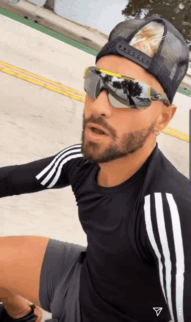 a man with a beard wearing sunglasses and a hat is sitting down