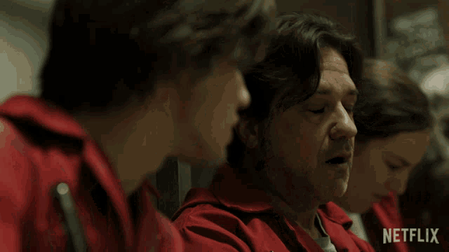 a group of people in red jumpsuits with a netflix logo on the bottom right