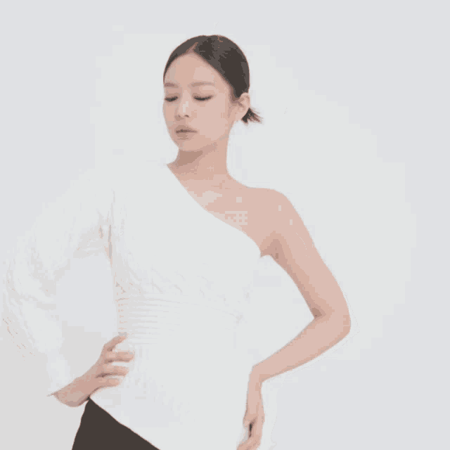 a woman wearing a white one shoulder top is standing in front of a sign that says real glow