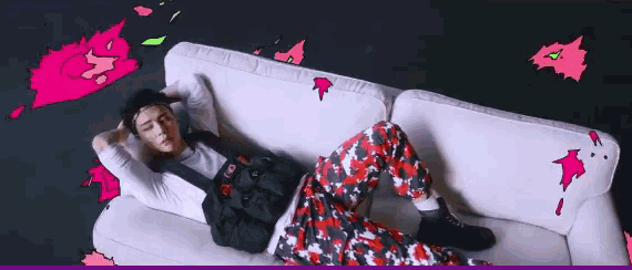 a man is laying on a white couch with his hands behind his head .