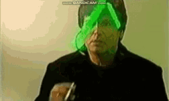 a man with a green glowing face is holding a pen .