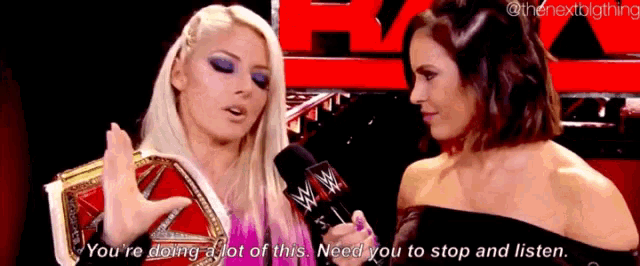 a female wrestler is talking to another female wrestler in front of a red background .