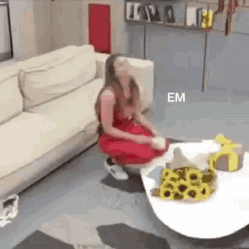 a woman in a red dress is sitting on the floor in front of a white couch .