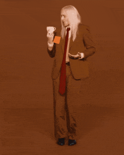 a man in a suit and tie is dancing and holding an orange card