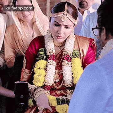 a bride and groom are getting married in a traditional indian wedding ceremony in front of a crowd .