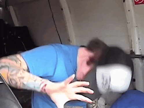 a man in a blue shirt with a tattoo on his arm is taking a selfie