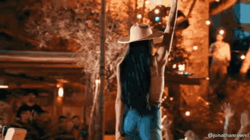 a woman wearing a cowboy hat is holding a guitar