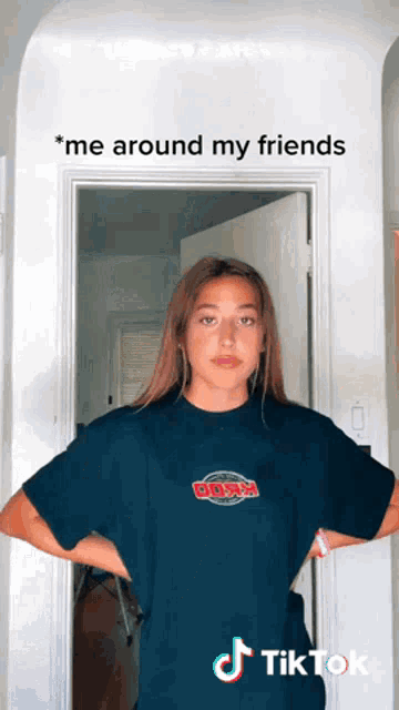a woman wearing a busch shirt stands in front of a door with her hands on her hips