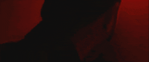 a person 's arm is visible in a dark room with a red light behind them .