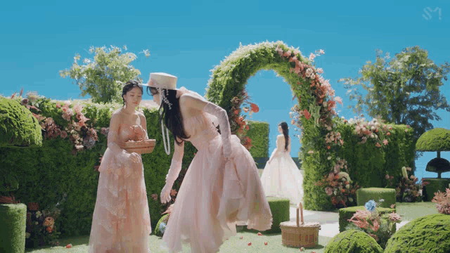 a woman in a pink dress holds a basket of flowers in a garden