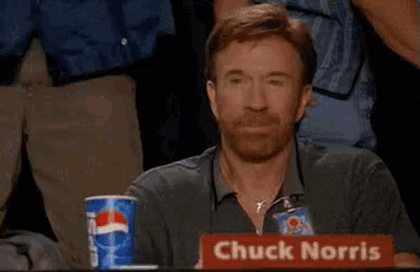 chuck norris is sitting at a table with a cup of pepsi