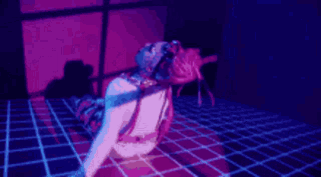 a woman is crawling on the floor in a dark room with purple lights behind her .