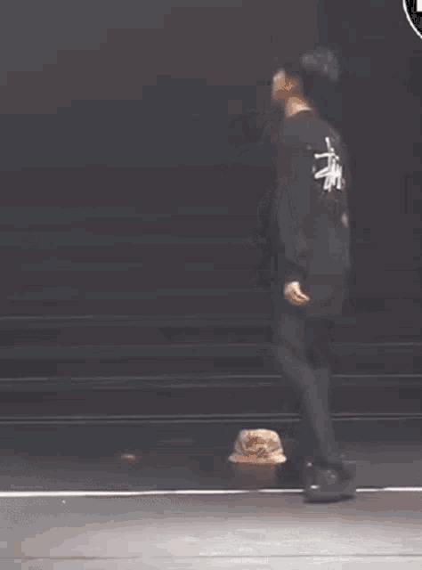 a man is kneeling down on a stage while wearing a black shirt and black pants .