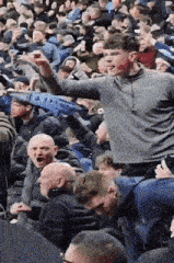 a crowd of people sitting in a stadium with a man raising his arms