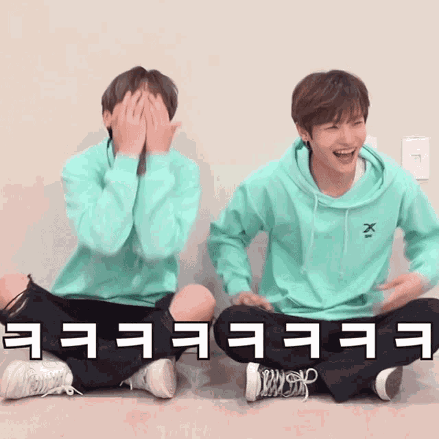 two young men sitting on the floor covering their faces with their hands and the words " eeee " written in white