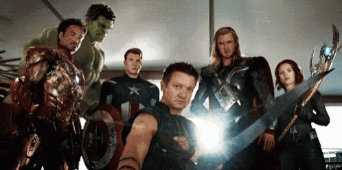 a group of avengers are standing next to each other in a room .