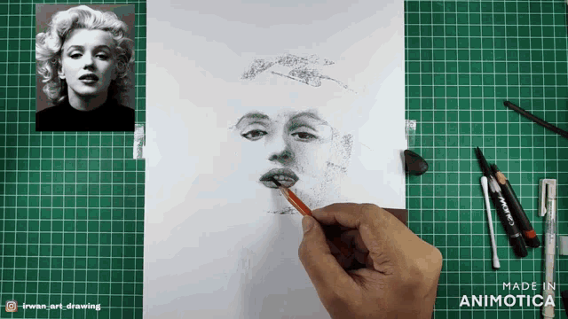 a drawing of marilyn monroe is being made on a green mat